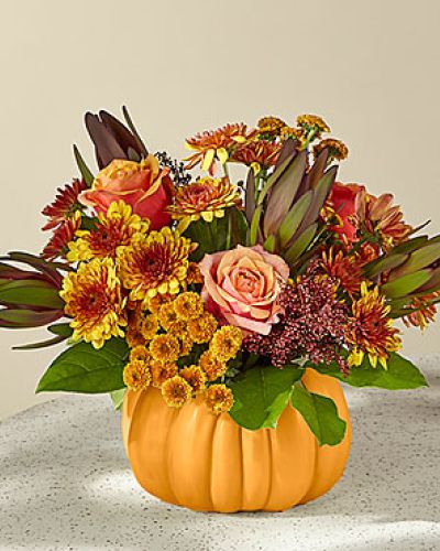 <p>Red Leucadendron, bicolor orange roses and roasted bronze cushion pompons add depth and vintage autumnal warmth to this festive arrangement—and your space.</p>