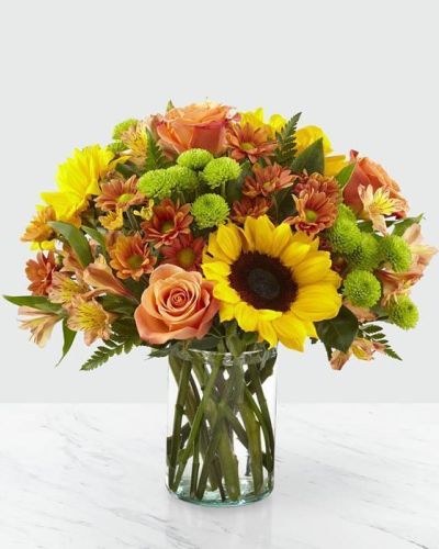 <p>Say hello to autumn with this bouquet filled with bold harvest hues and luscious blooms. Thoughtfully arranged with the freshness of fall in mind, a collection of orange roses, bright sunflowers and orange alstroemeria is set beautifully in a clear glass vase. Whether it's seasonal décor for your home or a gift for a loved one, our Autumn Magnificence Bouquet is sure to make any home its placed in feel warm and bright.</p>